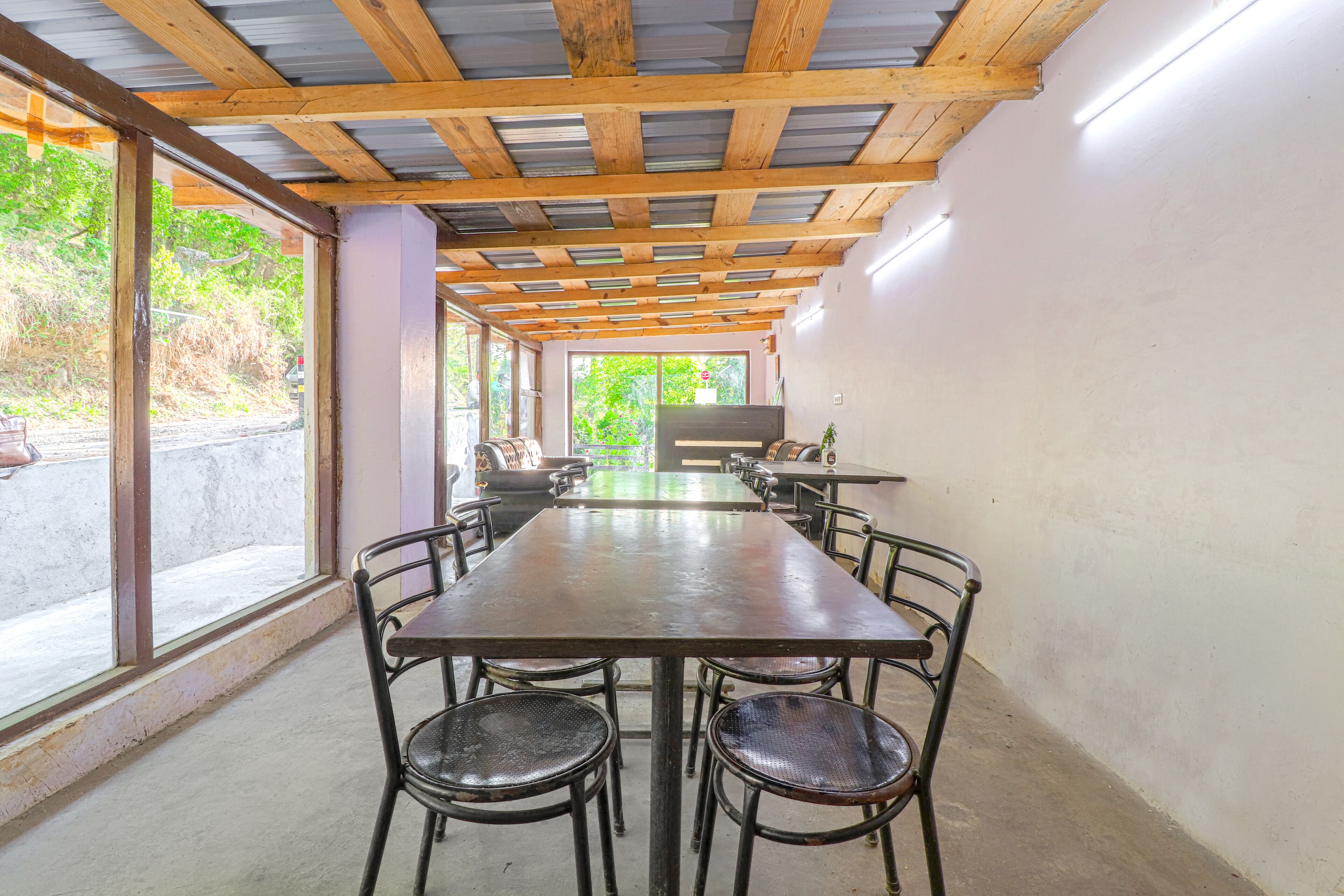 Una larga mesa de comedor con sillas, techo de madera y ventanas amplias.