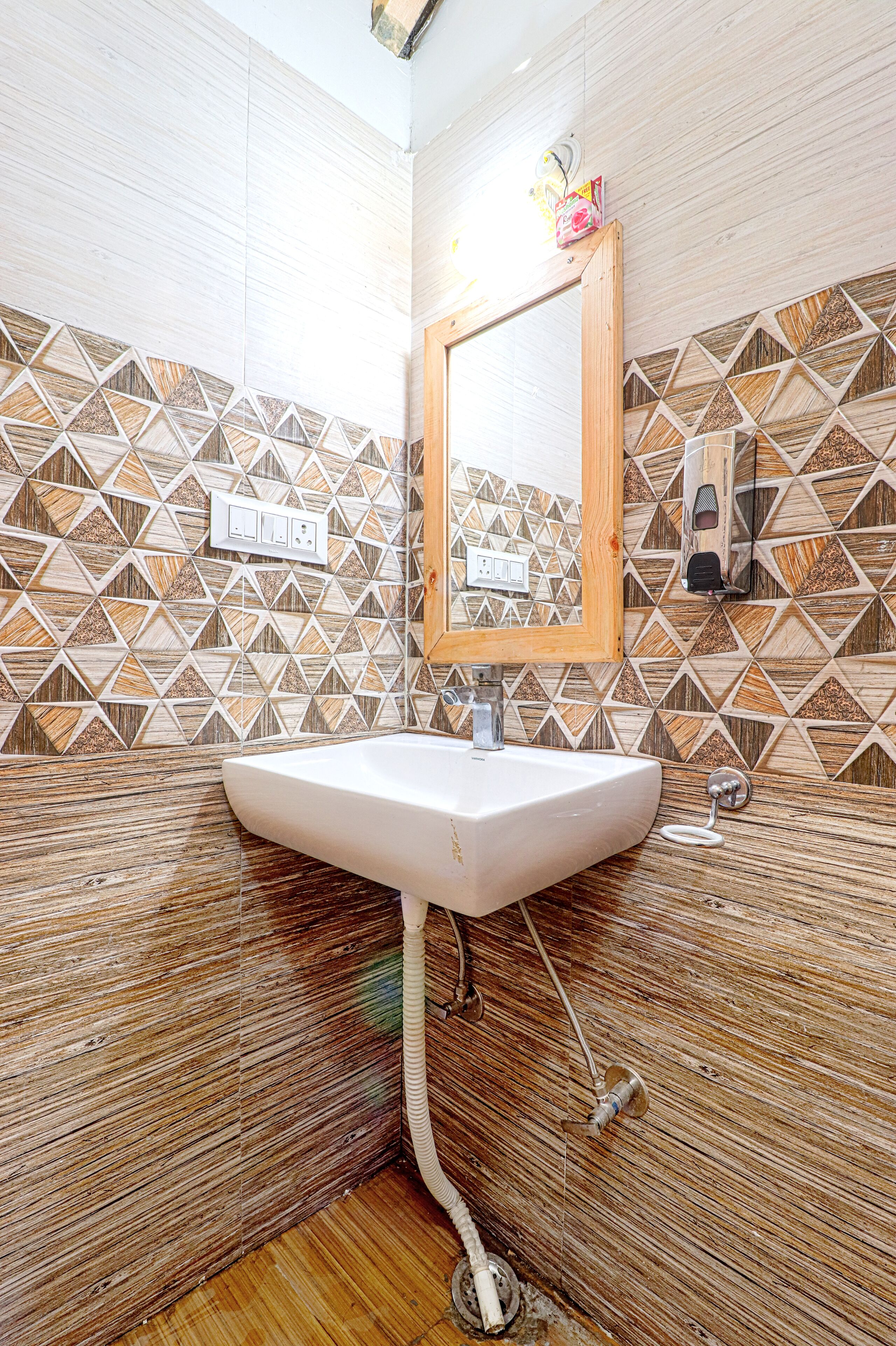 A bathroom with a white sink, wooden vanity, and patterned tile walls.