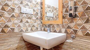 A bathroom with a white sink, wooden vanity, and patterned tile walls.