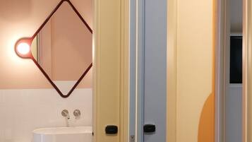 Un baño con un lavamanos blanco, un espejo de marco geométrico y una lámpara colgante.
