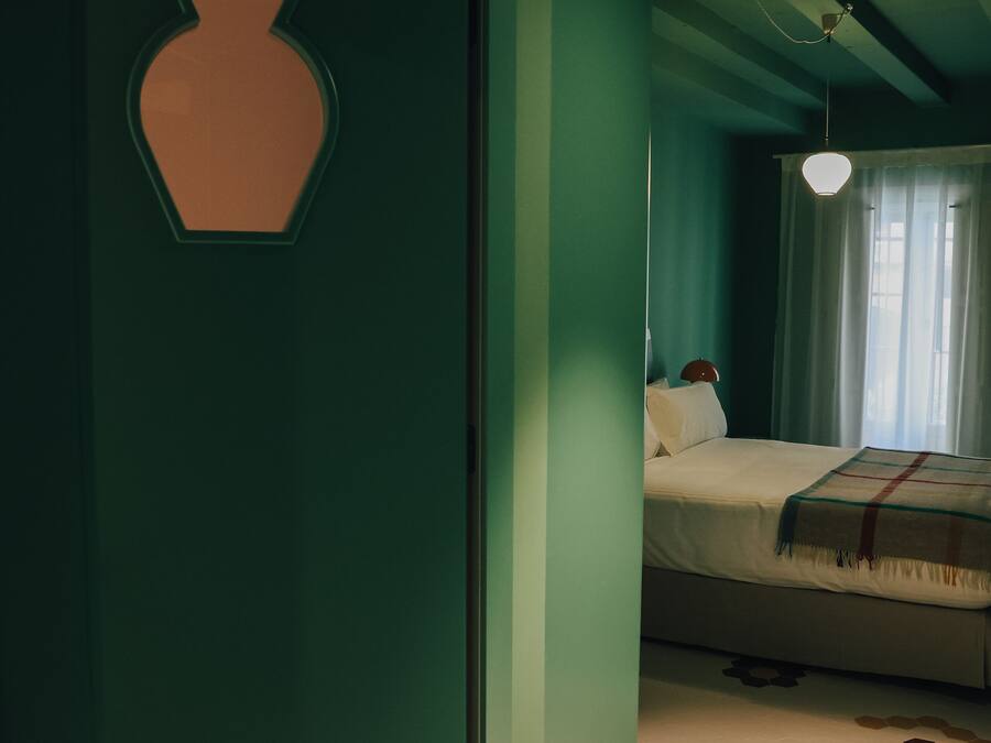 A bedroom with a bed, a bedside table, and a wall with a geometric design.
