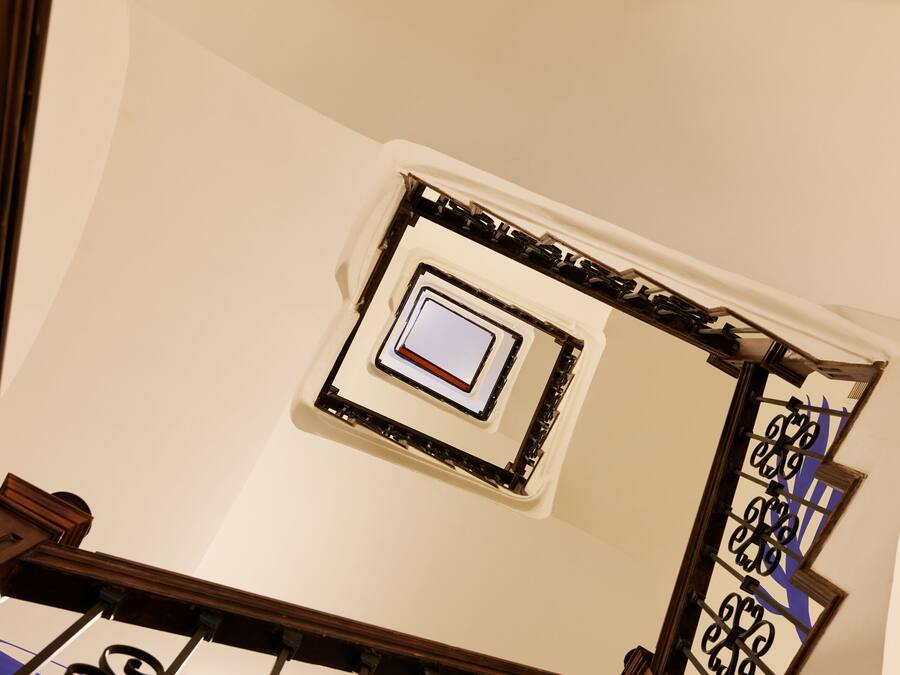 Una escalera de caracol con barandillas de metal ornamentales y un cuadro en la pared.