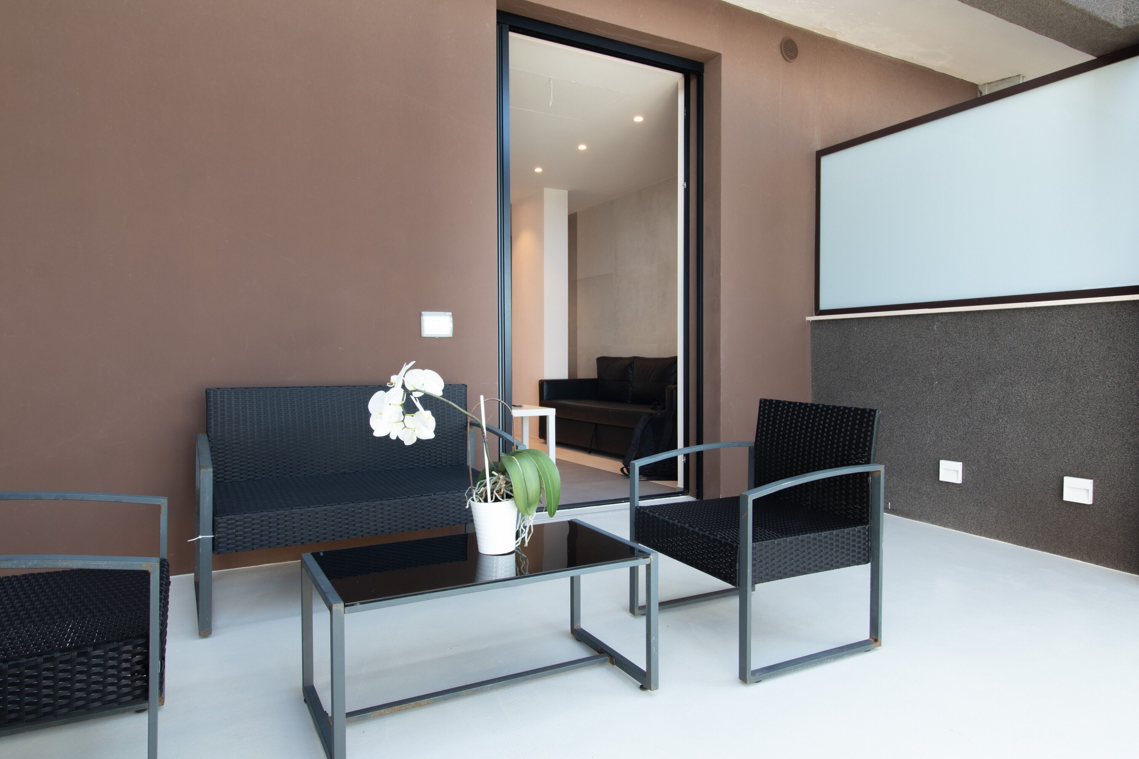 A modern room with a sofa, two chairs, a coffee table, and a potted plant.