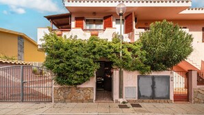 Ein zweigeschossiges Haus mit Steineinfahrt, einem Balkon und einer Satellitenschüssel.