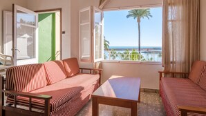 Ein Zimmer mit zwei gestreiften Sofas, einem Holztisch und Blick aufs Meer.