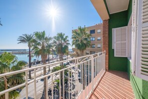 Un balcone con vista su un porto turistico, palme e un edificio dalla facciata verde.