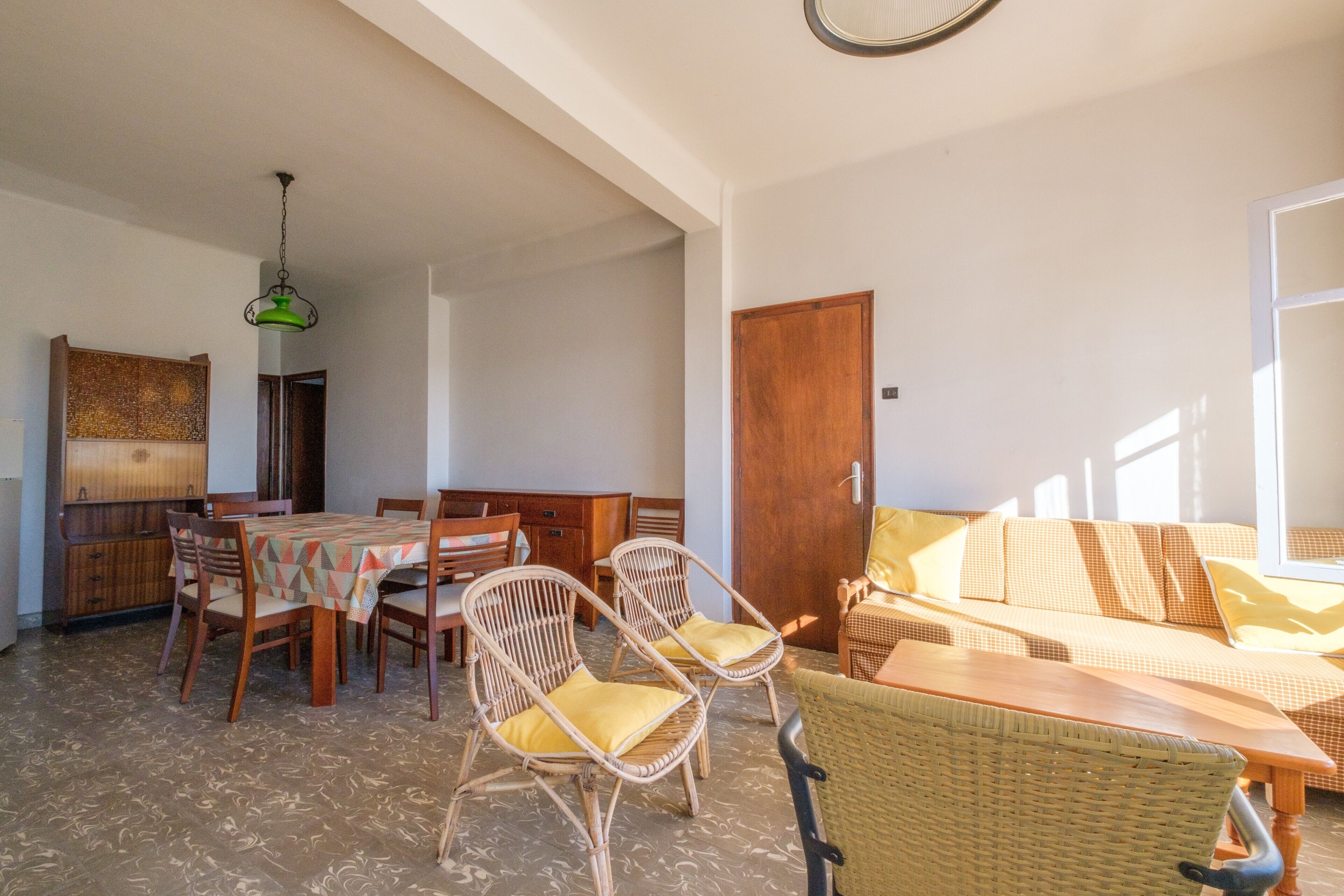 Un comedor con una mesa, sillas, un sofá y una puerta de madera.
