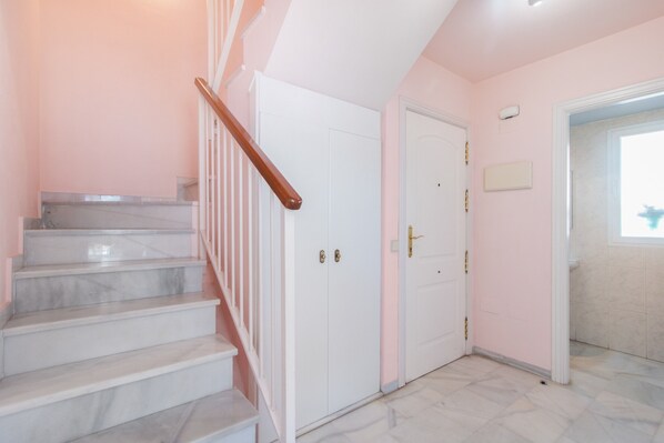 A staircase with marble steps and a wooden handrail leading to a white door with a gold handle. - Apartment 'Penthouse' with Sea View, Wi-Fi and Air Conditioning (Marbella)