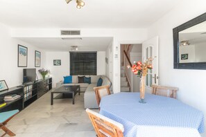 Un saló modern amb un sofà, una taula de cafè i una taula de menjador amb un ram de flors.