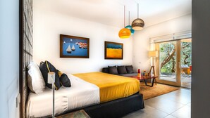 Ein modernes Schlafzimmer mit Bett, Kunstwerken und Blick durch eine Glastür.