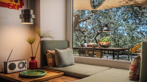 Un coin salon confortable avec vue sur un espace de restauration en plein air, une radio et un vase avec des plantes.