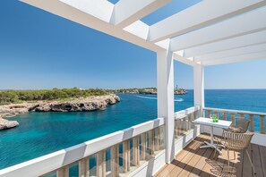 Un balcon avec vue sur la mer, une table avec des chaises et une bouteille d’eau.