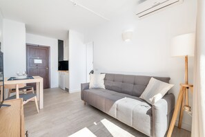 Una sala de estar moderna con un sofá gris, una mesa de centro de madera y un comedor con sillas.