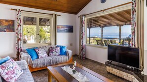 Un salon confortable avec un canapé, une télévision et de grandes fenêtres donnant sur la mer.