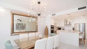 Una cocina moderna con gabinetes blancos, electrodomésticos de acero inoxidable y una isla central.