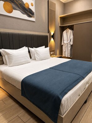 A hotel room with a large bed, a wardrobe, and a mirror.