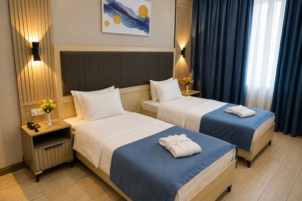 A hotel room with two beds, a nightstand, a lamp, and a painting on the wall.