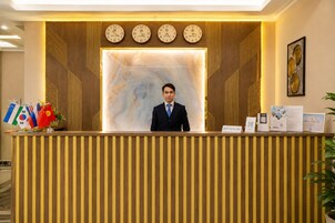 A reception desk with a clock, flags, and informational brochures.