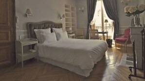 A bedroom with a large bed, a nightstand, a dresser, a chair, and a desk with a lamp. - Lafayette 75 M2 (Paris)