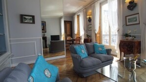 A living room with two grey sofas, a glass coffee table, and a wooden floor. - Lafayette 75 M2 (Paris)