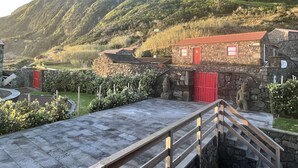 A stone building with red doors and windows, surrounded by a stone staircase and a paved area. - Stylish 2 Bedroom Stone House With Stunning Views, São Jorge, Azores (Vista) (São Jorge)