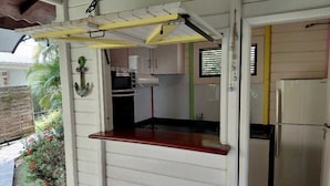 Una cocina compacta con armarios blancos, encimera roja y un refrigerador pequeño.
