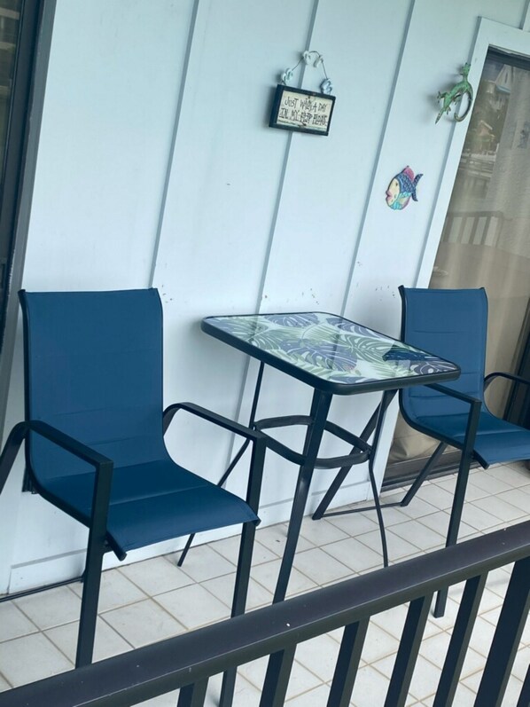 Un pequeño espacio al aire libre con dos sillas azules y una mesa de vidrio.