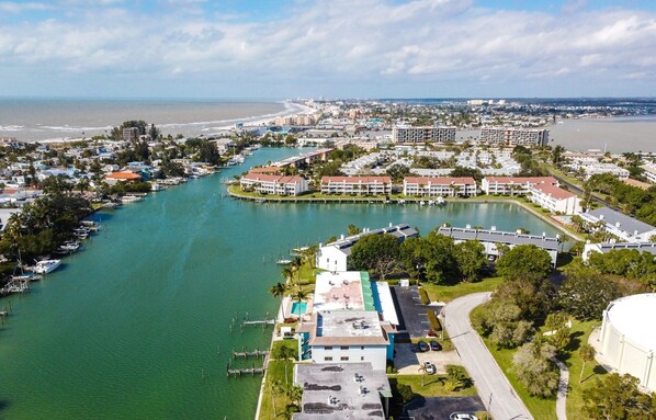 An aerial view of a coastal town with a marina, residential buildings, and a large white building with a green roof. - Treasure Island escape. Dolphins, manatees & beach (Treasure Island)
