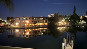 A waterfront building with multiple balconies and a dock extending into a calm lake.