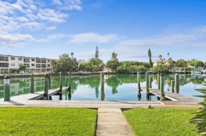Een jachthaven met een rustig wateroppervlak, een houten steiger en een gazon op de voorgrond.