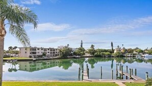 A lake with a dock, surrounded by greenery and buildings.