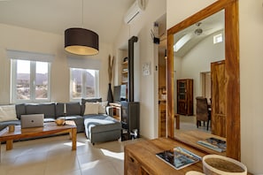 Una sala de estar moderna con un sofá, una mesa de centro, una laptop, una chimenea y un comedor con una mesa y sillas de madera.