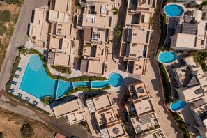 An aerial view of a residential area with multiple buildings, a large central swimming pool, and smaller pools.
