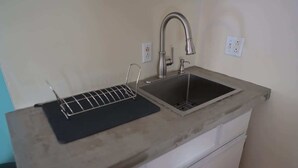 A kitchen with a double sink, a black cutting board, and a white countertop.