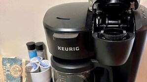 A Keurig coffee maker with a coffee pod holder and a mug.