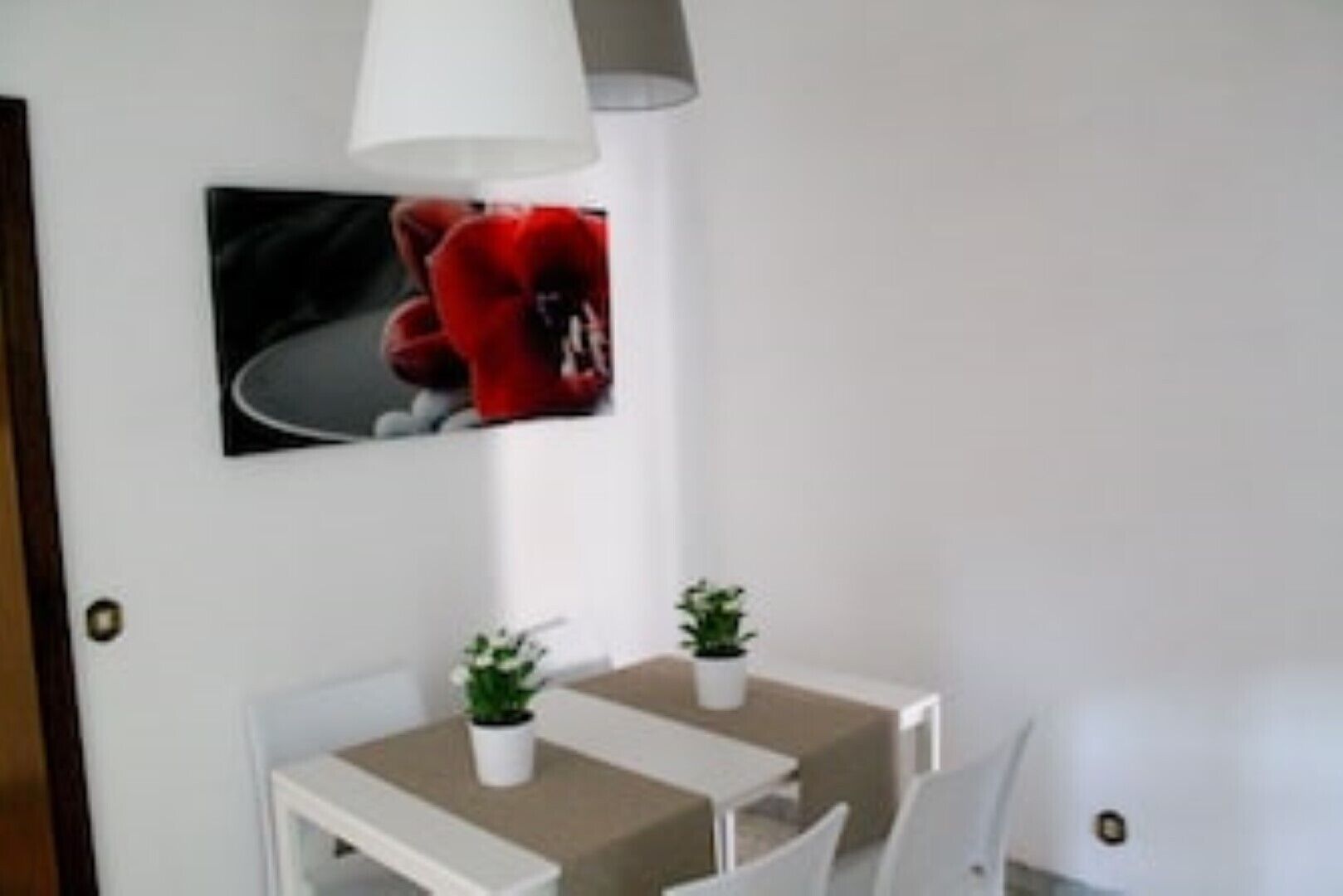 Ein kleiner Essbereich mit einem weißen Tisch, zwei Stühlen und einem Blumentopf.