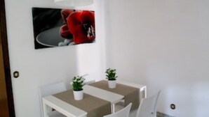 Un petit coin repas avec une table blanche, deux chaises et une plante en pot.