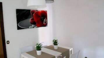 Ein kleiner Essbereich mit einem weißen Tisch, zwei Stühlen und einem Blumentopf.
