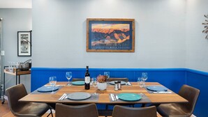 Ein Essbereich mit einem Holztisch, gedeckt für vier Personen, blauen Tellern und einer Weinflasche.