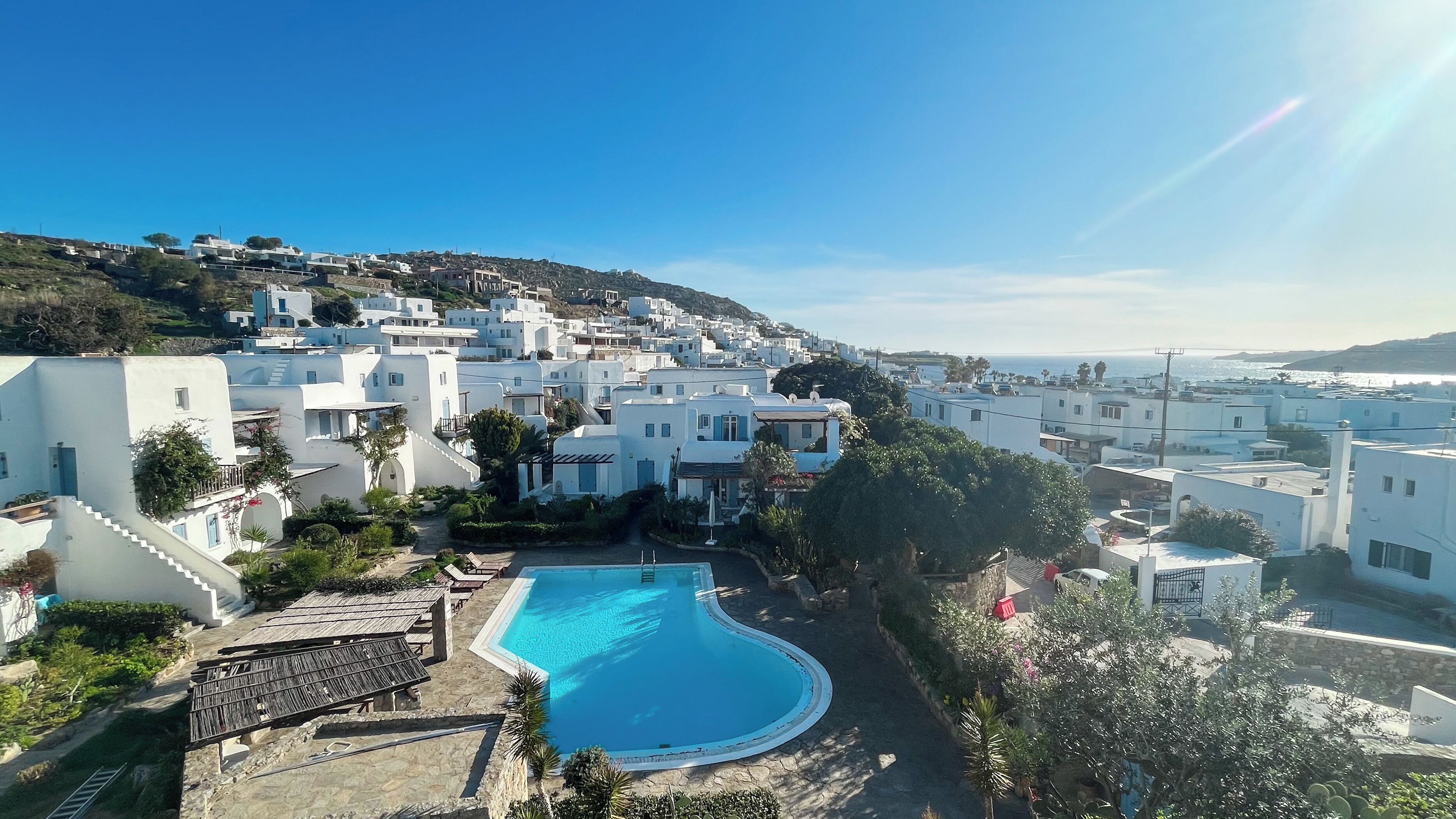 A coastal resort with white buildings, a swimming pool, and a view of the sea.