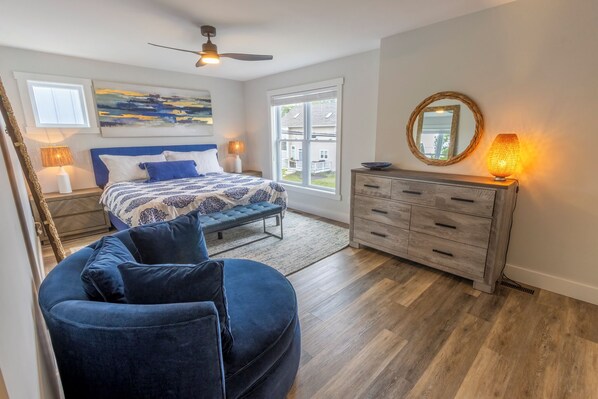 A bedroom with a bed, a blue armchair, a dresser, and a ceiling fan. - Walk to Beach, Brand New Townhouse with EV Charging (Michigan City)