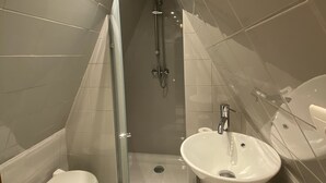 Ein modernes Badezimmer mit einer gläsernen Duschkabine, einer Toilette und einem Waschbecken.