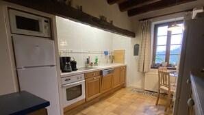 Eine Küche mit Fliesenboden, Holzschränken, einer Mikrowelle, einer Kaffeemaschine und einem Fenster mit Blick.