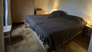 Ein Schlafzimmer mit Bett, Kleiderschrank, Nachttisch und Lampe.