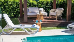 A poolside area with lounge chairs, a small table with drinks, and a sofa. - Nautical Views - Airlie Beach (Airlie Beach)