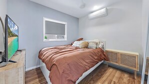 A bedroom with a bed, a television, a window, and a ceiling fan. - Nautical Views - Airlie Beach (Airlie Beach)