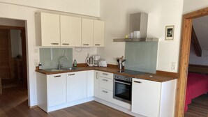 A modern kitchen with white cabinets, a wooden countertop, a built-in oven, and a stainless steel range hood. - Stylish vacation apartment in an old farmhouse - south view (Kirchbach)
