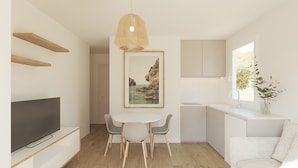 A modern kitchen with white cabinets, a dining area with a round table and chairs, a hanging light fixture, and a framed picture on the wall. - Lavendel Apartments (Ses Salines)