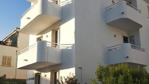 A modern multi-story building with balconies, a stone wall in the foreground, and a clear sky. - Lavendel Apartments (Ses Salines)