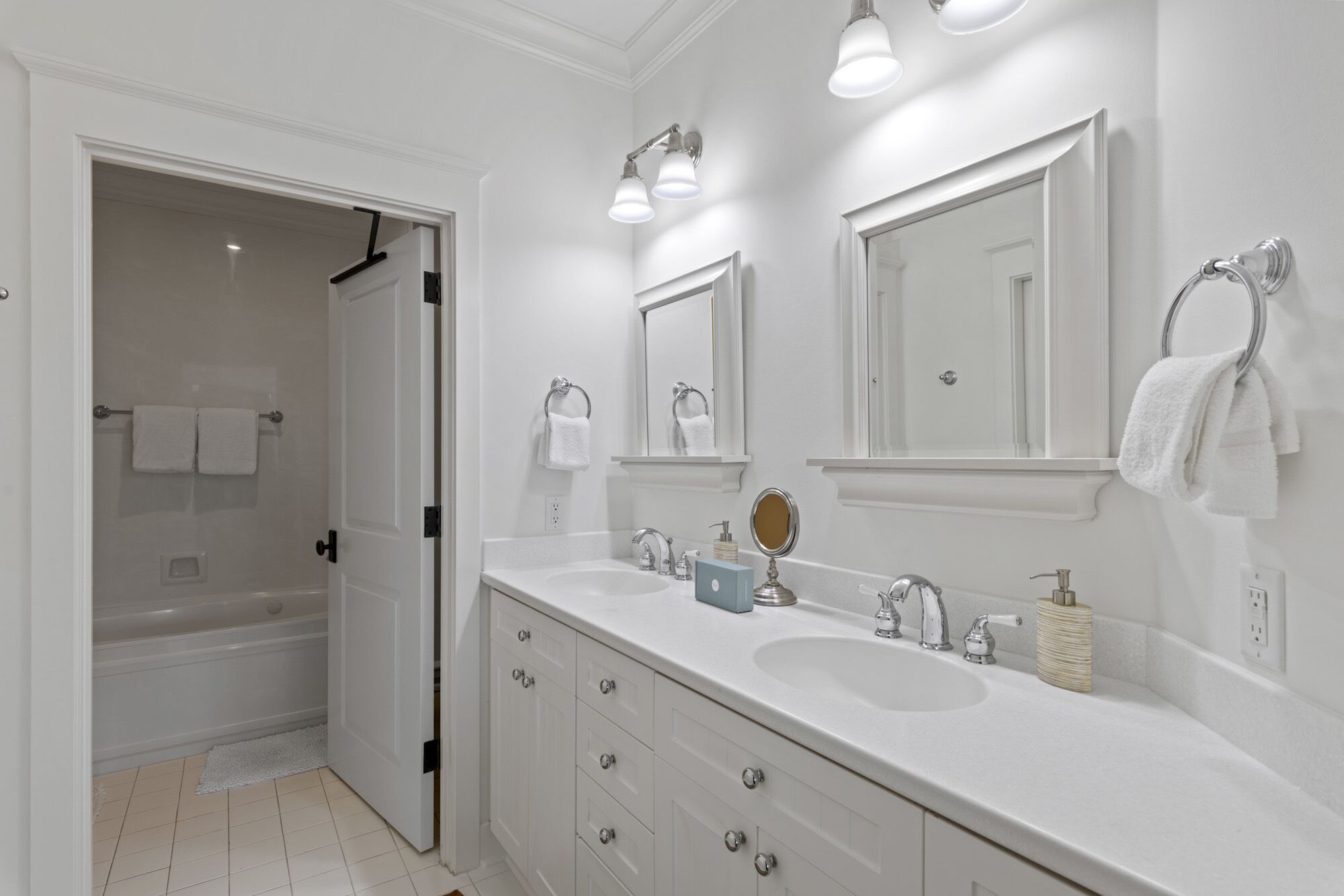 A modern bathroom with a double sink, a large mirror, and a shower area.